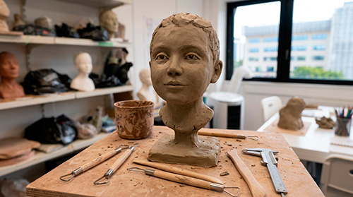 Élève sculptant un visage en argile pendant un cours Edumanga près de Versailles